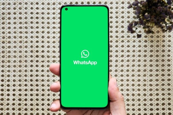 WhatsApp logo on a phone held in hand. WhatsApp logo on a phone held in hand.