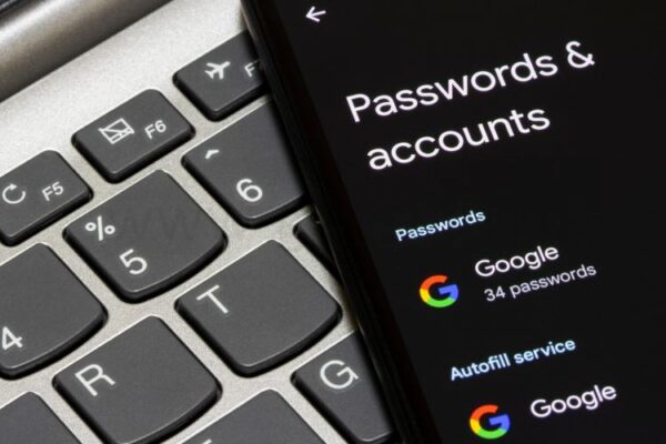 учетная запись Google и пароль на экране смартфона рядом с ноутбуком