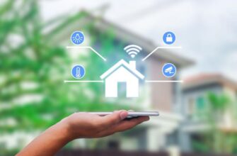 Рука с смартфоном с приложением для умного дома на фоне размытого дома.
