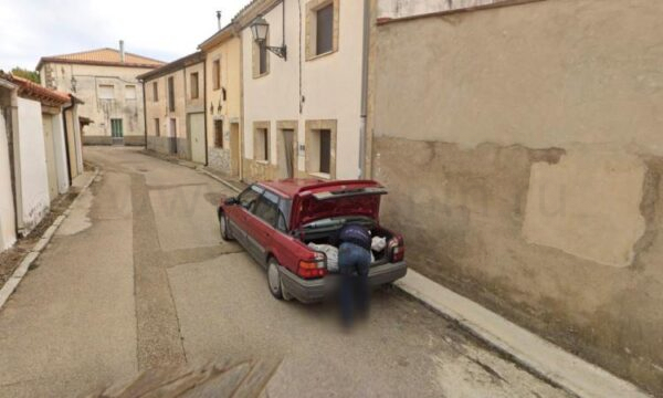 Изображение Google Street View, на котором кто-то загружает большой сверток в багажник автомобиля.