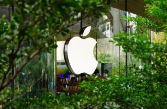 Логотип Apple на здании среди деревьев.