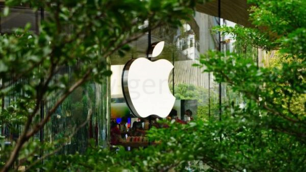 Логотип Apple на здании среди деревьев.