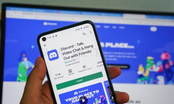 Человек с смартфоном, где открыто приложение Discord.
