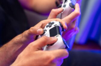 Человек держит контроллер PlayStation 4 DualShock 4 белого цвета.