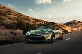 Передний вид нового Aston Martin Vanquish Volante, движущегося по побережью на фоне маяка.
