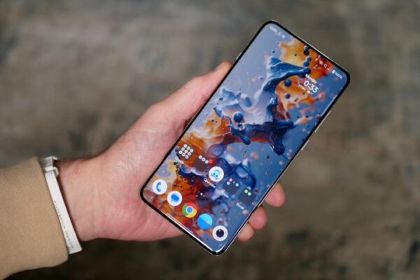 Человек держит OnePlus 13, показывая экран.