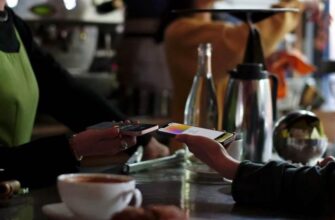 Пользователь iPhone оплачивает в кафе с помощью Apple Wallet.