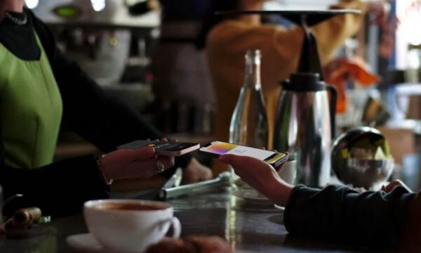 Пользователь iPhone оплачивает в кафе с помощью Apple Wallet.