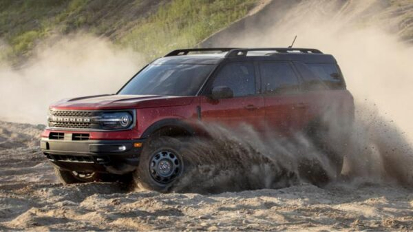 Передний вид красного внедорожника Ford Bronco Sport 2021 года, который движется по песку.
