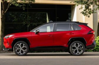 Static side profile shot of a red 2025 Toyota RAV4 PHEV XSE parked outside of a modern building.