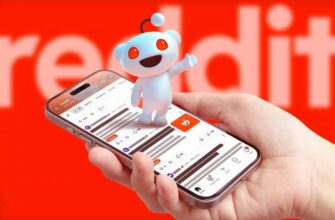 Рука держит телефон с открытым Reddit, маскот Reddit на экране, логотип размытый на заднем плане.