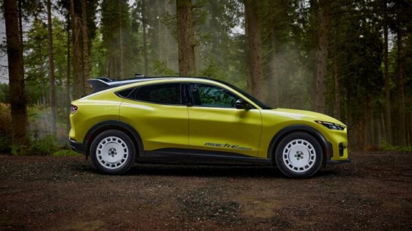 Static side profile shot of a yellow Ford Mustang Mach-E Rally parked in a forest.