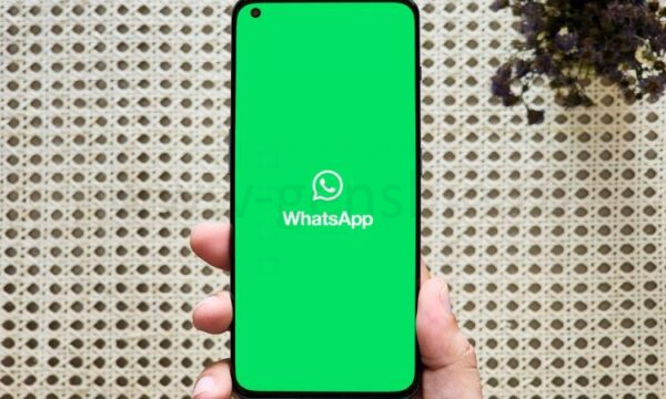 WhatsApp logo on a phone held in hand.