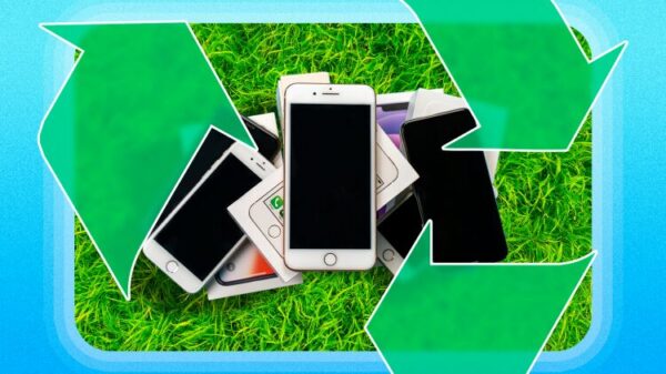 A pile of old phones on the grass with a recycling icon.