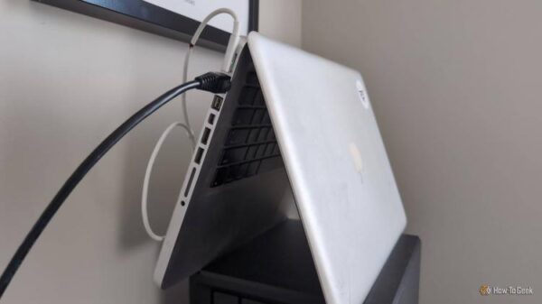 An old MacBook laptop stood in the tent position with an Ethernet cable plugged into it.