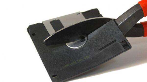 A 3.5 inch floppy is cut in half by shears.