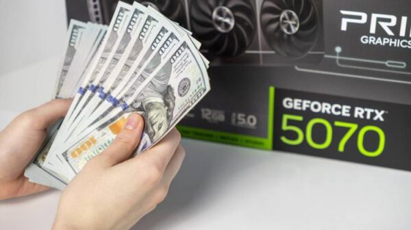 A pair of hands hold money in front of a GPU box.