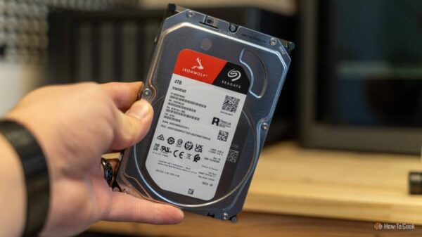 A hand holding a Seagate IronWolf 4TB hard drive at an angle showing the label and specs.