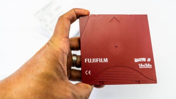 A hand holds an LTO tape.
