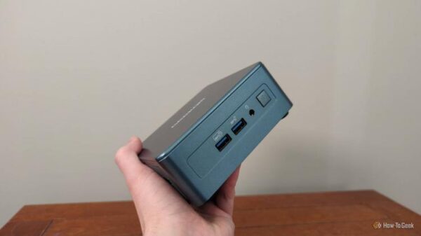 A person's hand holding a Geekom mini PC.-1