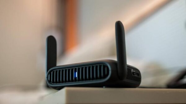 TP-Link BE3600 Wi-Fi travel router sitting on a table in a hotel room.