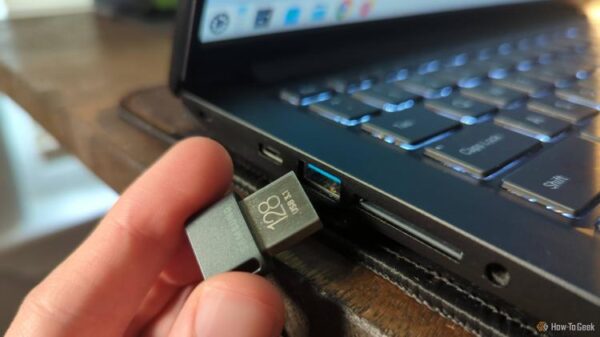 Person's hand putting a USB drive in a laptop port.