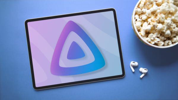 Планшет с логотипом Jellyfin на экране, лежащий рядом с миской попкорна и беспроводными наушниками.