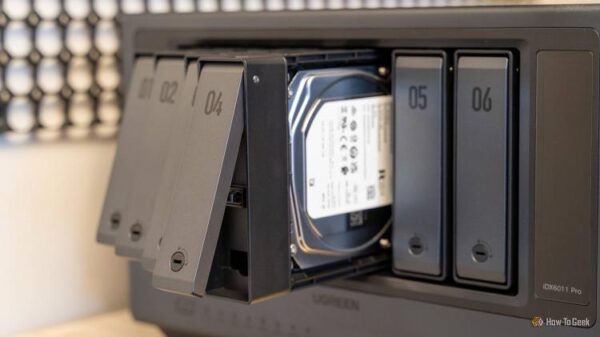 Multiple drive trays pulled out from the Ugreen iDX6011 Pro NAS with a hard drive visible inside the bay.